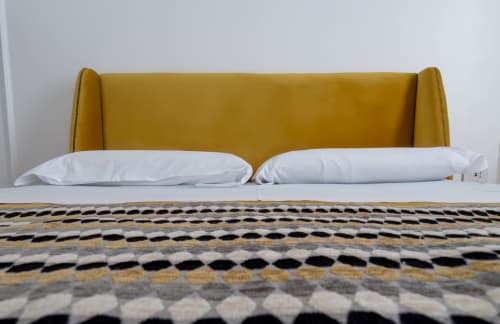 Mustard yellow upholstered bed headboard with white pillows and patterned bedding at Garibaldi 125 Naples