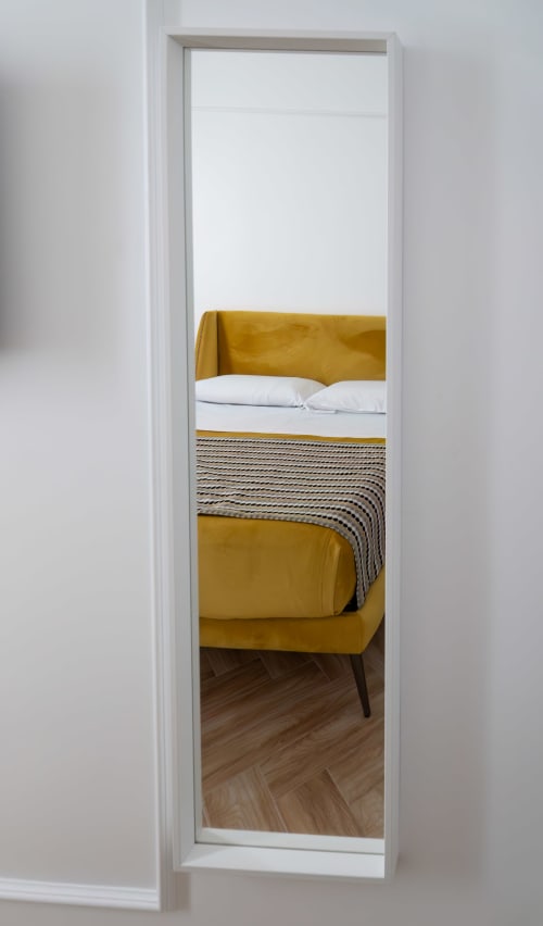 Golden upholstered bed with white pillows and striped throw at Garibaldi 125 in Naples, viewed through doorway with
