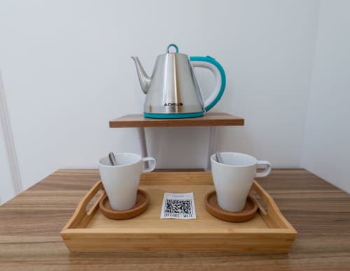 Modern tea service setup at Garibaldi 125 Naples with stainless steel kettle and white cups on wooden tray