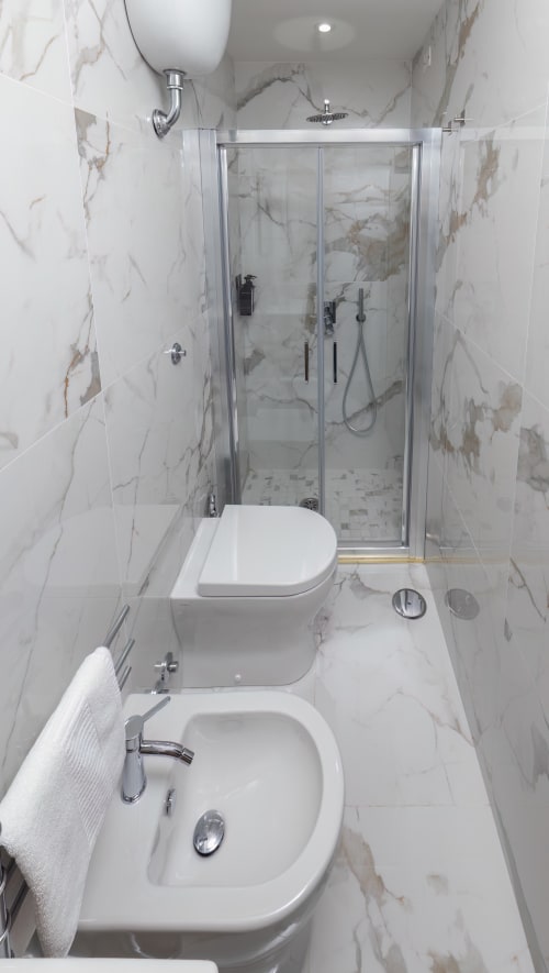 Modern marble bathroom at Garibaldi 125 Naples with double sinks, glass shower enclosure, and white fixtures