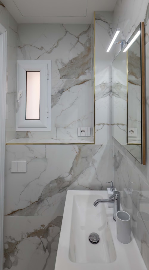 Modern marble bathroom at Garibaldi 125 Naples B&B with white sink, gold-framed mirror, and walk-in shower