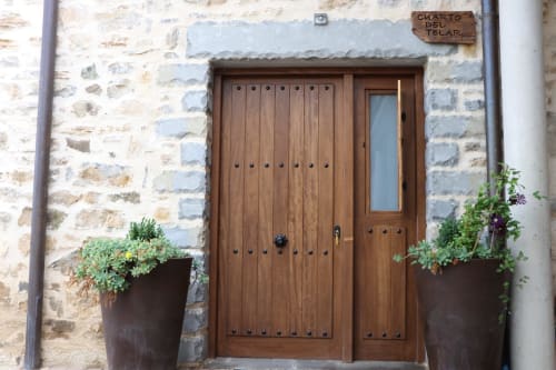 Puerta de entrada de madera del hotel Casa Lafuente en Lukiano, Araba, con plantas en macetas y fachada de piedra