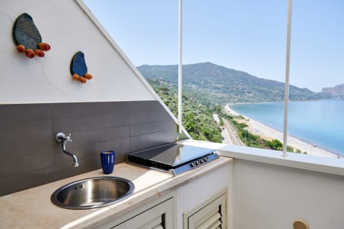 CefalHome kitchenette with coastal view, stainless sink, cooktop, and decorative prickly pear art