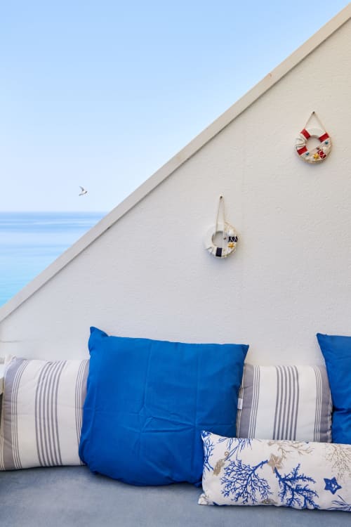 CefalHome coastal terrace with blue pillows, striped cushions, and nautical decor overlooking the sea