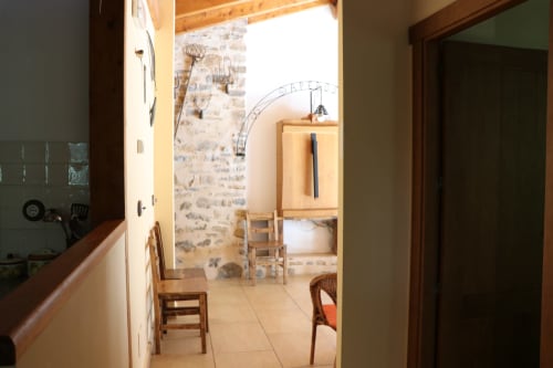Entrada rústica de Casa Lafuente con muros de piedra expuesta, vigas de madera y acceso a sala con vistas a la montaña