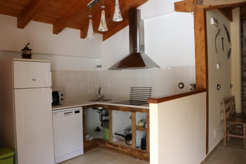 Cocina moderna en apartamento Casa Lafuente, Lukiano, con electrodomésticos blancos, vigas de madera e iluminación colgante