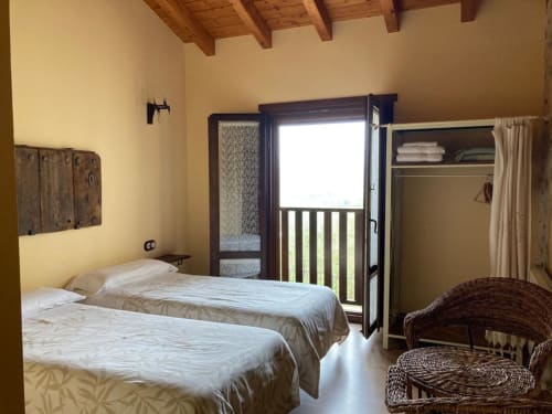 Dormitorio luminoso en Casa Lafuente con camas gemelas, vistas a la montaña desde el balcón y vigas de madera rústica