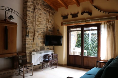 Amplia sala de estar en Casa Lafuente con chimenea de piedra, TV de pantalla plana, puertas de madera y vistas a las montañas