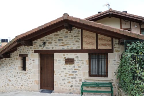 Exterior del apartamento Casa Lafuente en Lukiano, Araba - edificio de piedra con detalles de madera y banco verde
