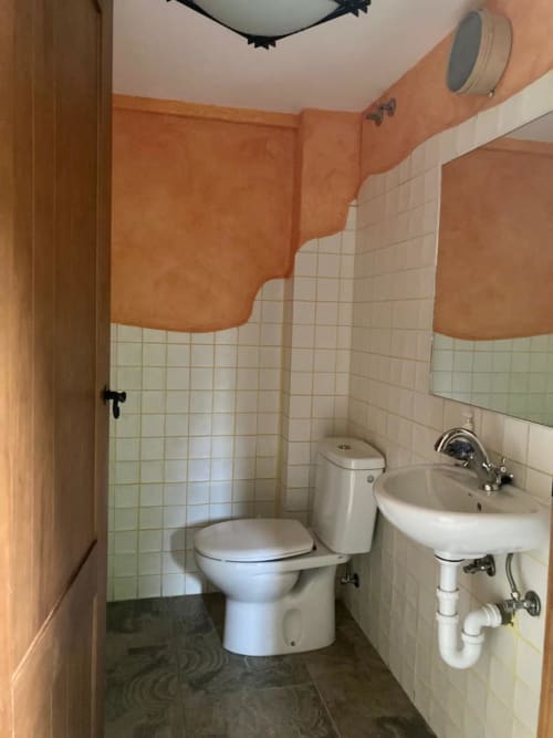 Baño del apartamento Casa Lafuente en Lukiano con inodoro, lavamanos y paredes de azulejos