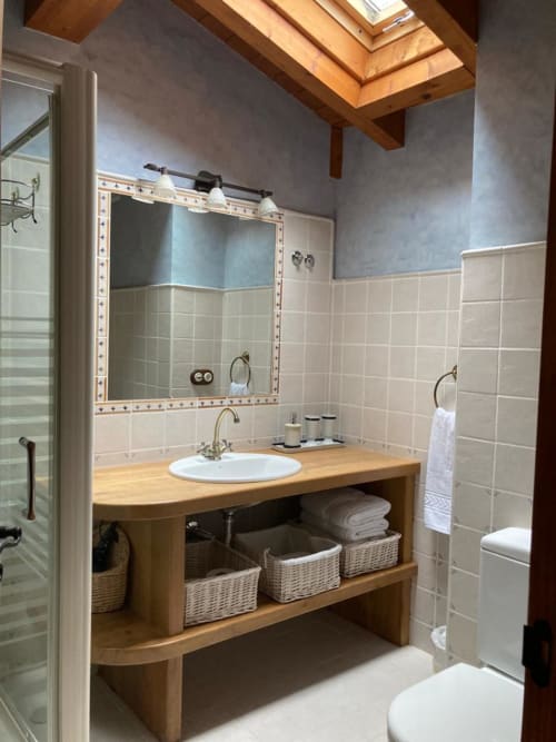 Baño moderno en apartamento Casa Lafuente con vanidad de madera, azulejos blancos tipo metro, espejo decorativo y claraboya