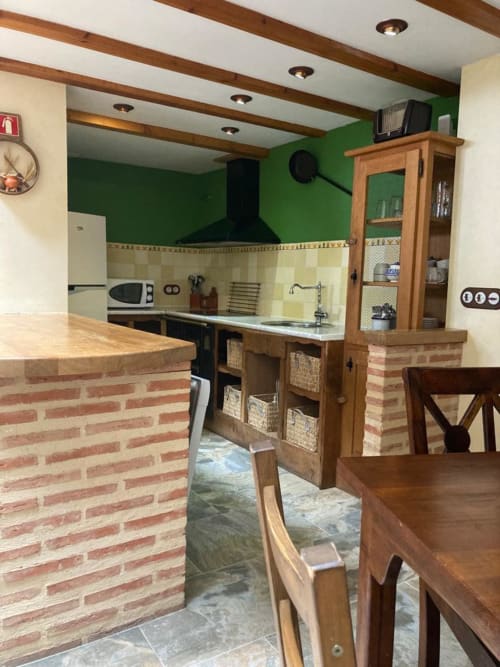 Cocina moderna en apartamento Casa Lafuente, Lukiano, con mostradores de ladrillo, paredes verdes, armarios de madera y zona de comedor