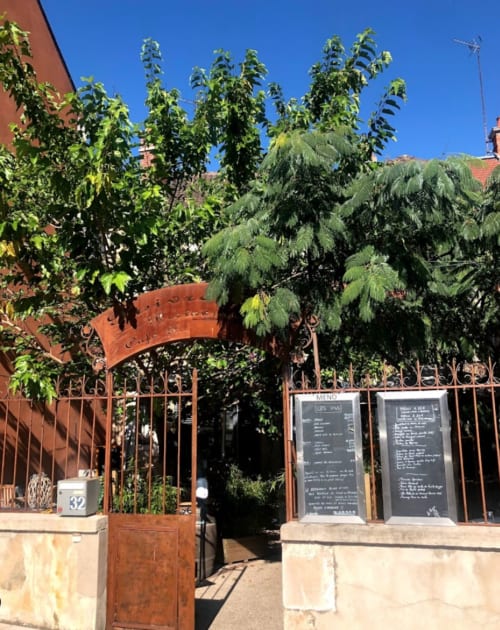 Rustic courtyard entrance at Domaine de l'Ocrerie with metal gate and garden plants in Pourrain