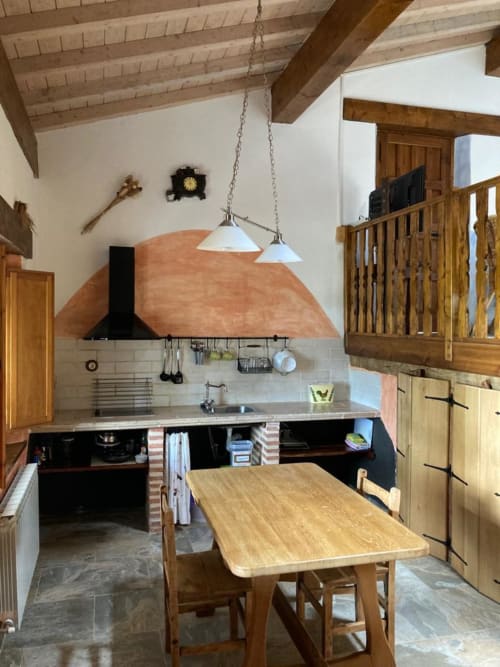 Cocina rústica con vigas de madera, campana de horno de barro, mesa de comedor y lámparas colgantes en el apartamento Casa Lafuente, Lukiano