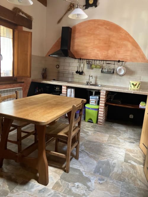 Zona de cocina-comedor en apartamento Casa Lafuente en Lukiano con mesa de madera, horno de barro y electrodomésticos modernos