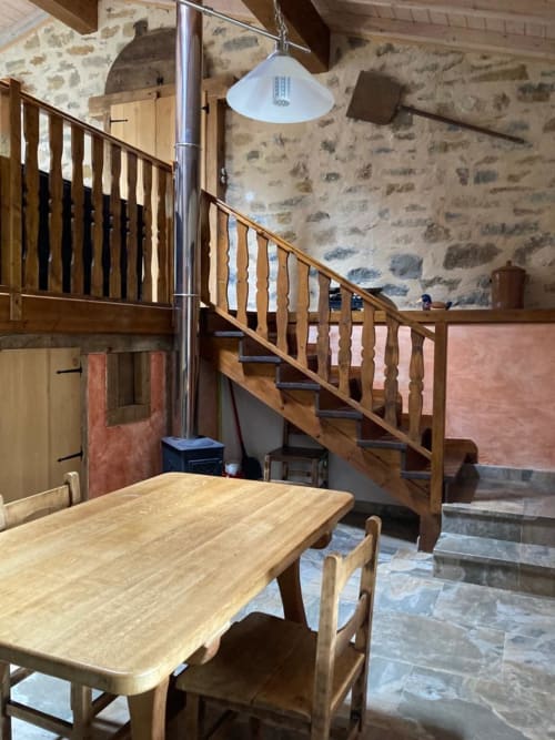 Interior rústico de piedra en Casa Lafuente con mesa de comedor de madera, escaleras y vistas a las montañas en Lukiano, Araba