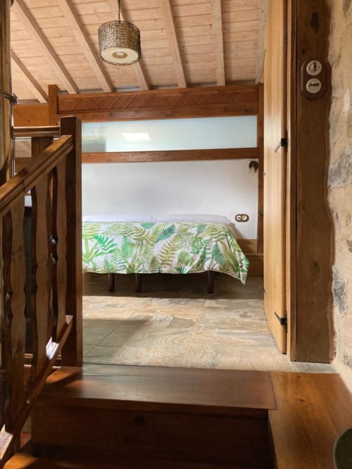 Dormitorio rústico en Casa Lafuente, Lukiano, con cama de madera y ropa de cama estampada con helechos