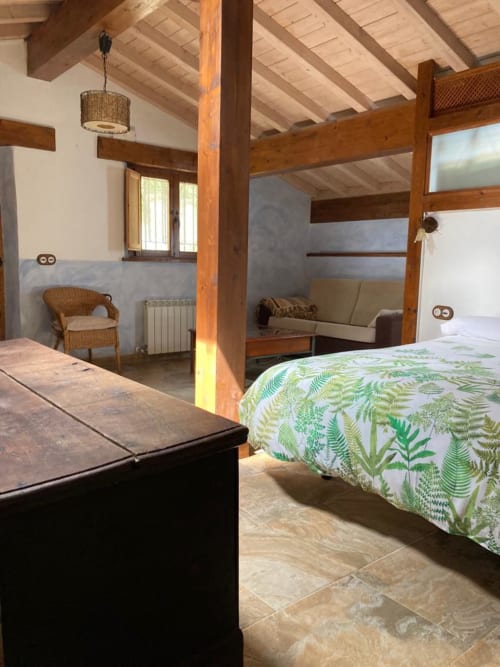 Amplio apartamento rústico en Casa Lafuente con vigas de madera vista, cama con ropa de helecho y zona de estar
