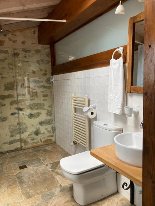 Baño moderno en apartamento Casa Lafuente en Lukiano con ducha a ras de suelo, azulejos blancos, vigas de madera y lavabo redondo