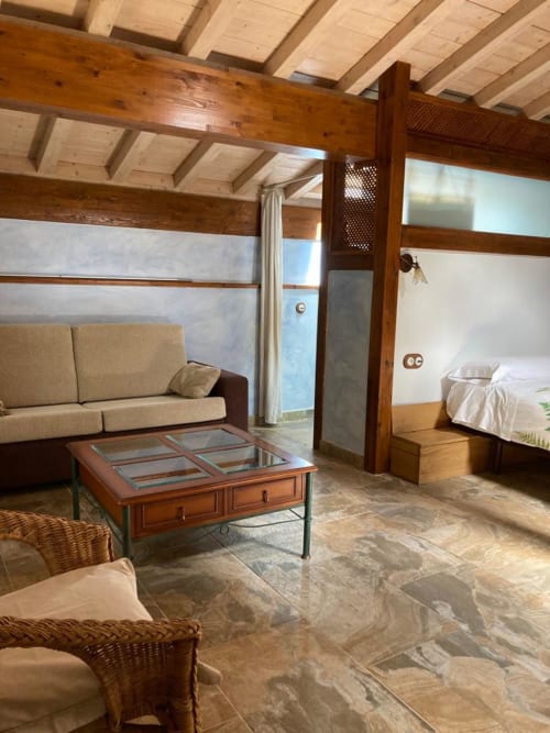 Amplia sala de estar en Casa Lafuente con vigas de madera, sofá beige y vistas a la montaña