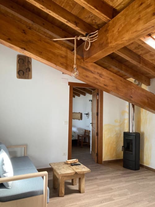 Interior rústico de apartamento en Casa Lafuente con vigas de madera vista, muebles de madera y tradicional estufa de chimenea