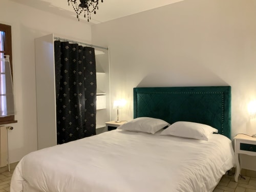 Spacious bedroom at Locacharme cottage in Blois with green upholstered headboard, white bedding, and elegant décor
