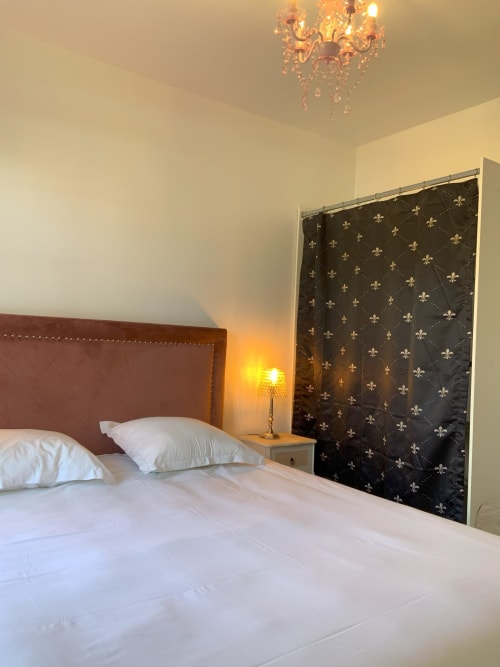Elegant bedroom at Locacharme cottage in Blois with burgundy headboard, white bedding, decorative curtains, and crystal