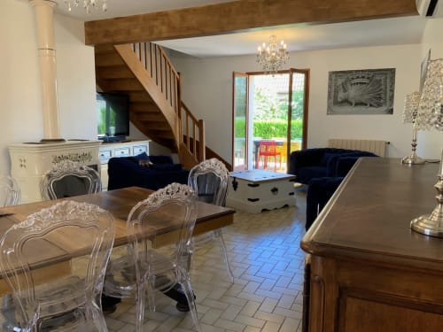 Elegant cottage living room in Blois with wooden stairs, crystal chandeliers, decorative chairs, and garden views