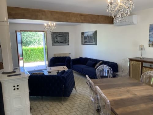 Spacious open-plan living area in Blois cottage with navy velvet seating, dining table, crystal chandeliers, and garden views