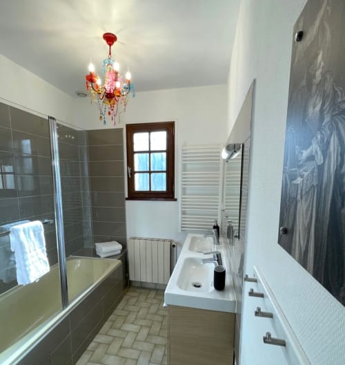 Modern bathroom at Locacharme cottage in Blois with double sink, walk-in shower, and colorful chandelier
