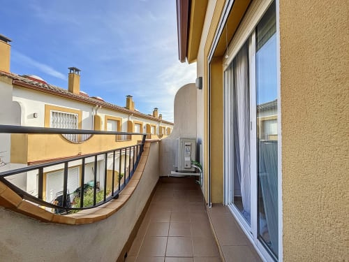 Terraza del cottage La Vela en Estartit Rental con barandilla curva que domina edificios con persianas amarillas en L'Estartit, España