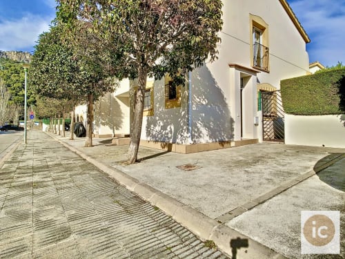 Casa rural en L'Estartit con paredes encaladas, árbol frondoso y terraza pavimentada