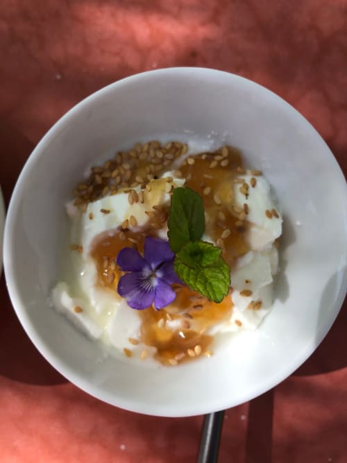 Elegante plato de postre en Domaine de l'Ocrerie con yogur cremoso, drizzle de caramelo, semillas tostadas y flor violeta