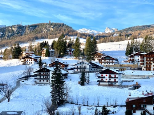 Appartamento GioviGemini in un villaggio alpino innevato con chalet, montagne e boschi di conifere a Treviso