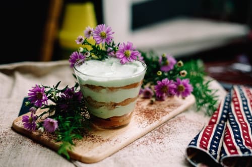 Dessert stratificato con topping di crema guarnito di fiori viola presso l'Apartment GioviGemini a Treviso, Italia