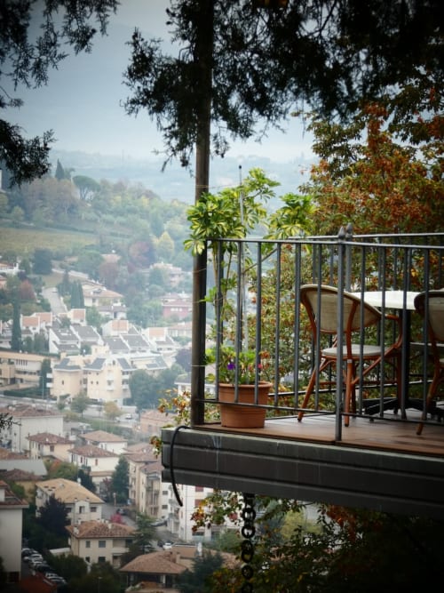 Balcone con vista sul paesaggio urbano di Treviso, vasi in terracotta e pavimento in legno dell'Apartment GioviGemini