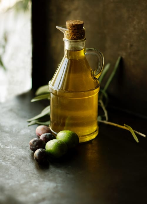 Bottiglia di olio d'oliva con olive fresche e rami presso Masseria Vittoria, rustico bed and breakfast italiano ad Acaya, Vernole