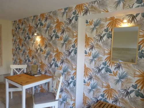 Tropical botanical wallpaper in Roseraie room at Villa Thébaïde, featuring gold and teal leaf patterns with wooden desk and