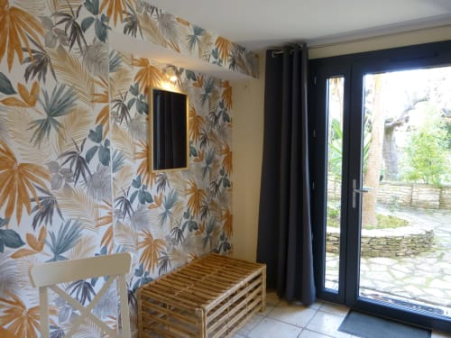Roseraie room at Villa Thébaïde with tropical palm wallpaper, garden view doors, and modern black framing