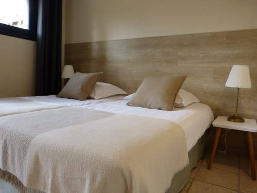 Twin beds with beige bedding and wooden headboard in Villa Thébaïde's Roseraie room, Laudun L'Ardoise