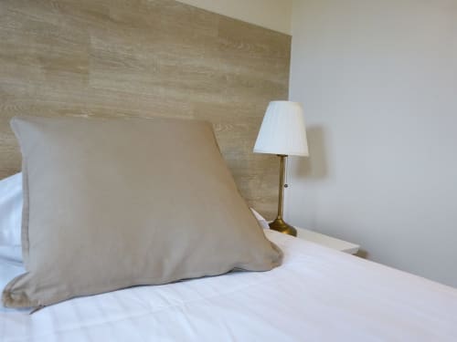 Beige pillow and white bedding with table lamp in Roseraie room at Villa Thébaïde, Laudun L'Ardoise