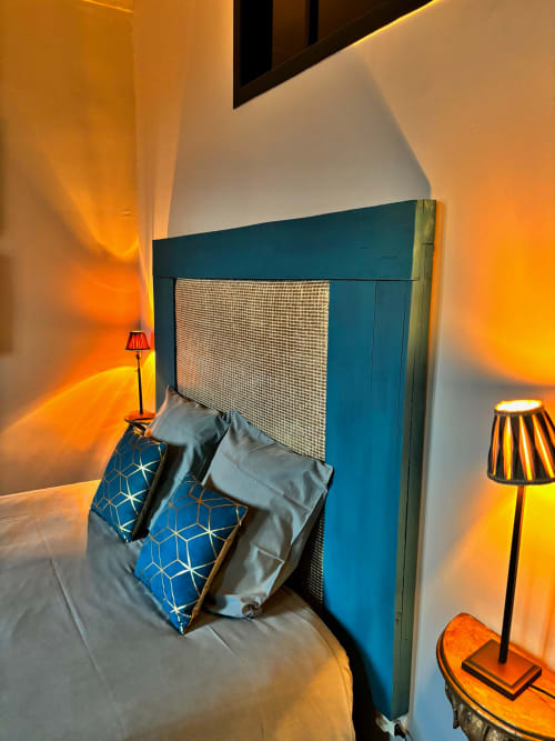 Lit avec tête de lit bleu-vert, oreillers à motifs bleus, éclairage chaleureux et lampes de chevet dans la chambre Pierre de Ronsard à La vie de
