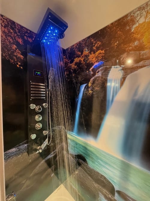 Luxueuse pomme de douche pluie avec éclairage LED bleu et cascade en arrière-plan au Gîte du Miroir Domérat