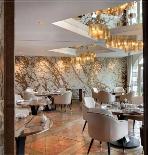 Elegant dining room at Domaine de l'Ocrerie with gold branch wall art, cream chairs, and skylight.