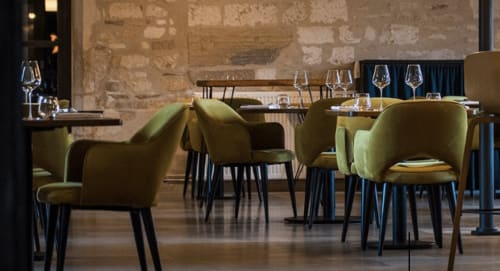 Elegant dining room at Domaine de l'Ocrerie with olive-green chairs, stone walls, and place settings in Pourrain