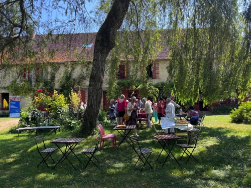 Outdoor courtyard gathering at Domaine de l'Ocrerie in Pourrain with picnic tables under a large willow tree