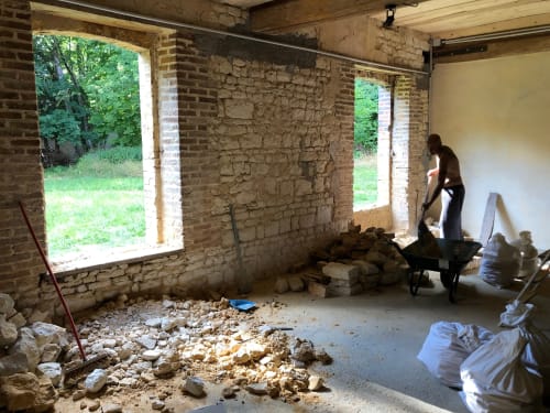 Interior renovation underway at Domaine de l'Ocrerie, stone walls exposed with debris and construction materials visible.