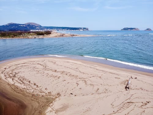 Playa arenosa de Estartit con un mar turquesa tranquilo, islas y montañas costeras bajo un cielo azul despejado