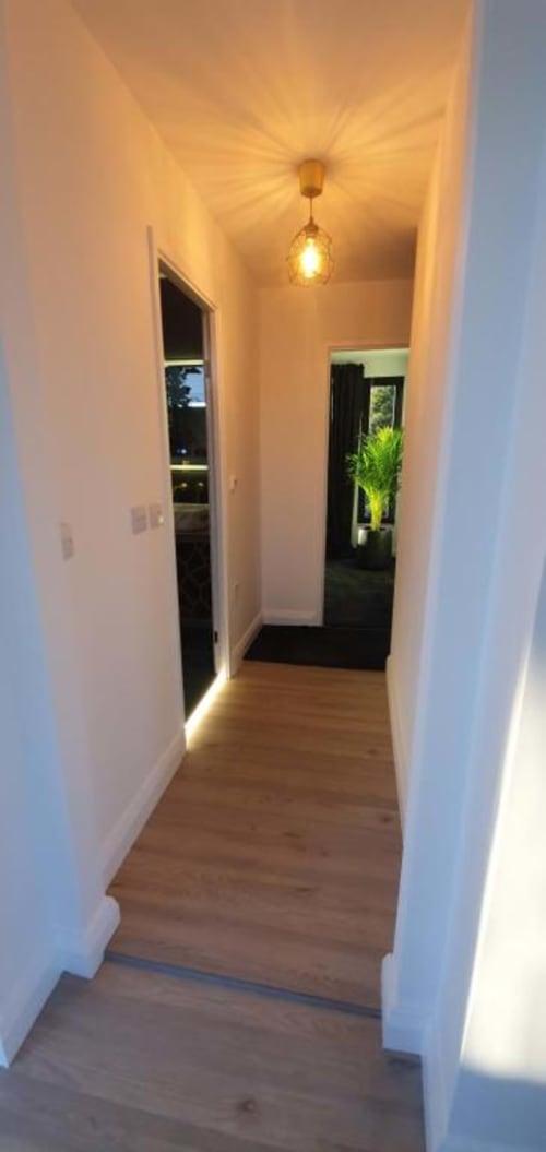 Modern hallway in Dublin Exchange Suites villa with wooden floors, white walls, pendant lighting, and garden views through