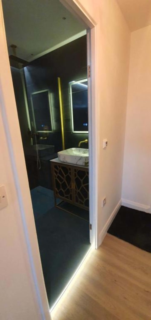 Modern bathroom at Dublin Exchange Suites with illuminated mirrors, sink vanity, and dark tiled flooring